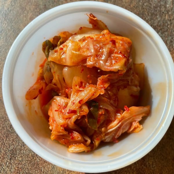 A white bowl filled with vibrant red kimchi from Sue's Kimbap House.