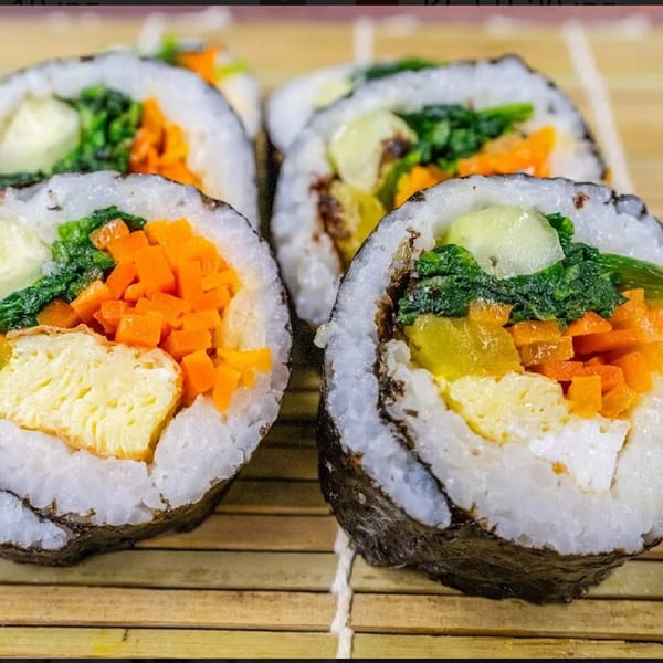 Close-up of several Sue's Kimbap House kimbap rolls with colorful vegetable and egg fillings.